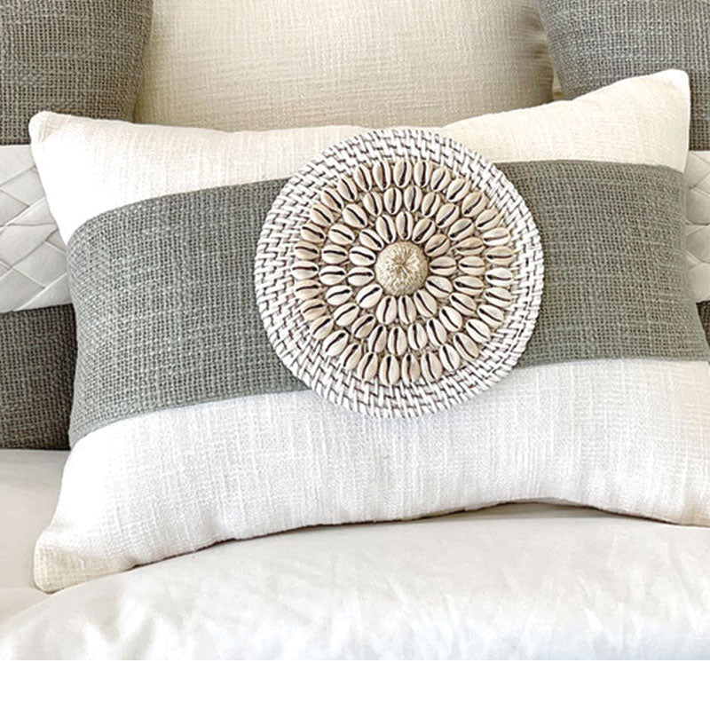 White coastal cushion with a sage colour sash, wrapped around the lumbar cushion with shell and rattan detail is a must for a coastal style. 